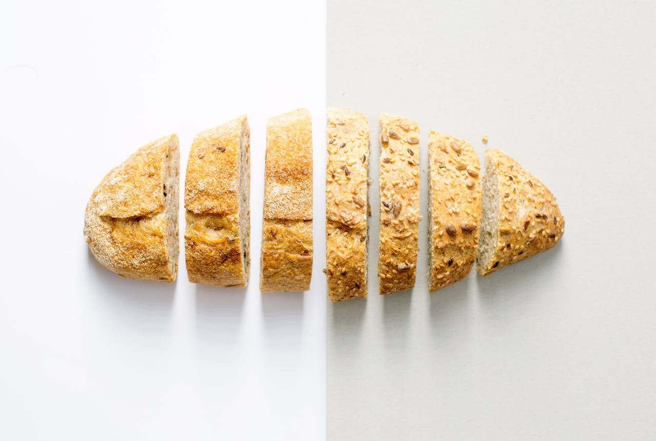 Freshly baked whole wheat bread sliced on a white background, showcasing its homemade texture.