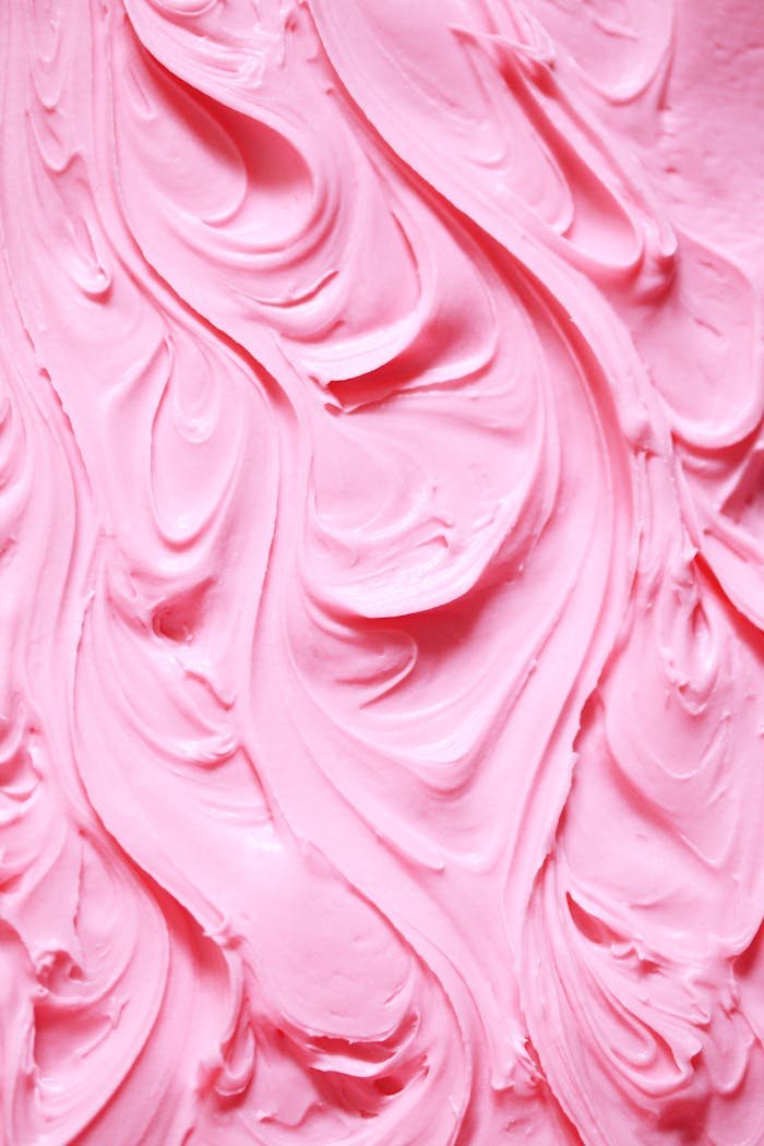Detailed swirls of creamy pink frosting creating a textured background ideal for design.